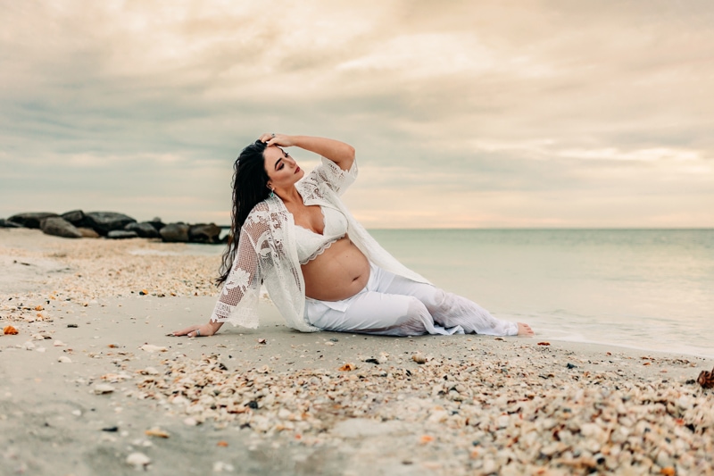 siesta key, maternity photographer, a pregnant woman sitting on the sand at the edge of the water