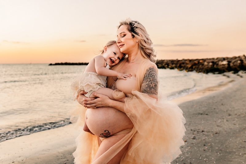 Family photography, Anna Maria Island, maternity photographer, a pregnant mother on the beach hugging her baby